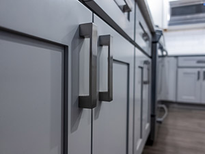 Low angle view of gray kitchen cabinet door handles inside a large, beautiful kitchen with finished, hardwood floors